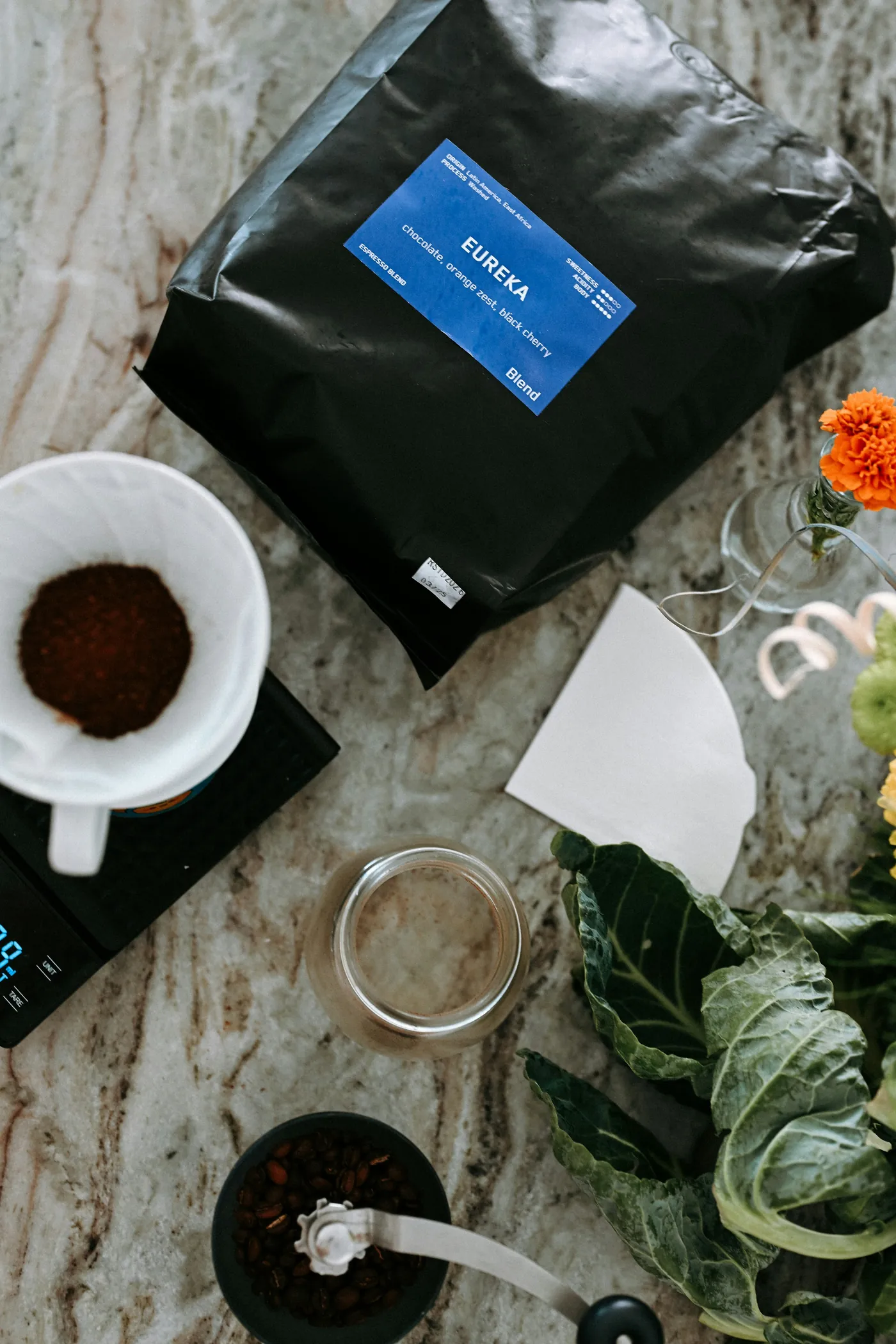 An editorial flat-lay of brewing gear: scales, V60, kettle, grinder.