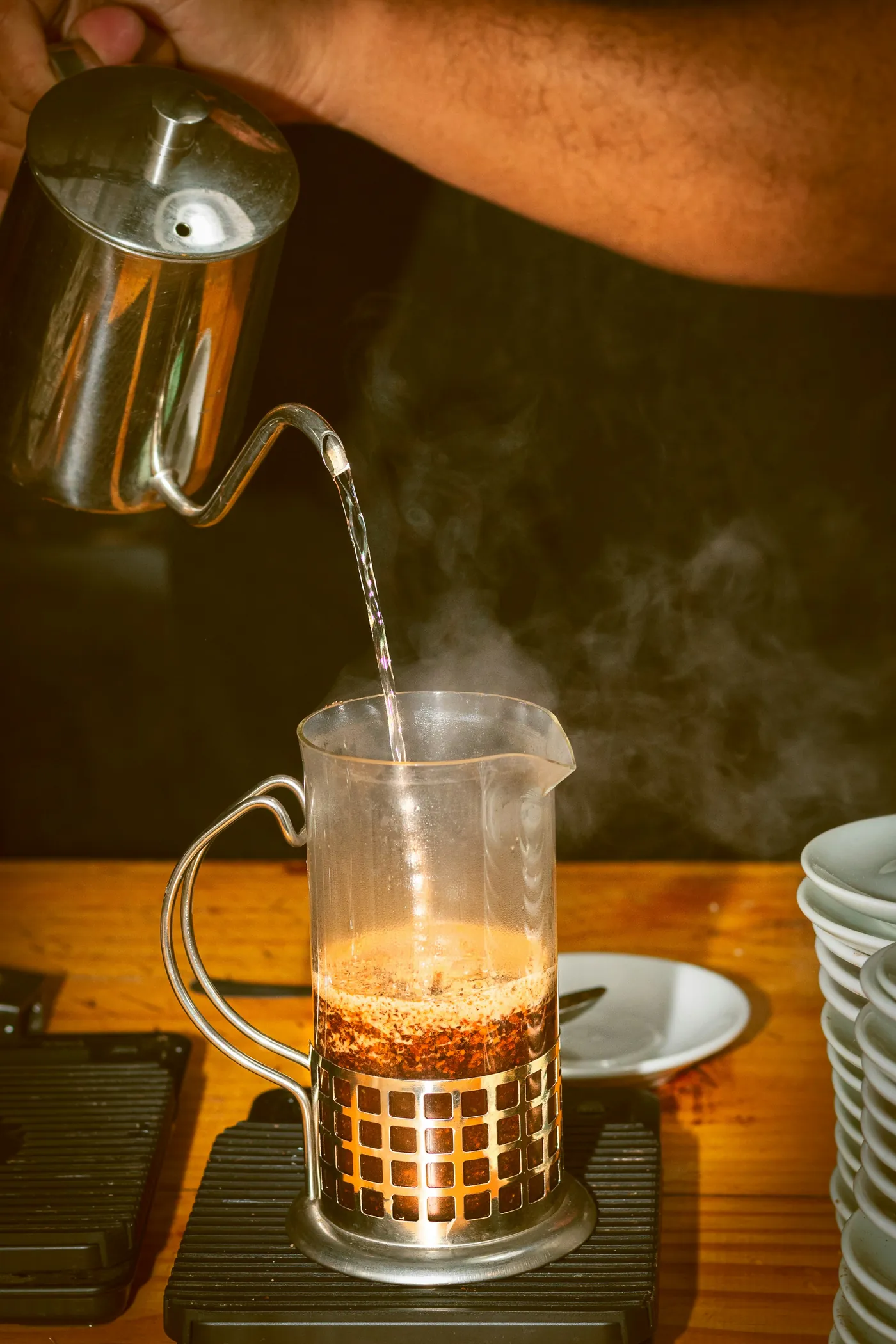 A slow, intentional pour of espresso into a glass demitasse under warm, filtered light.